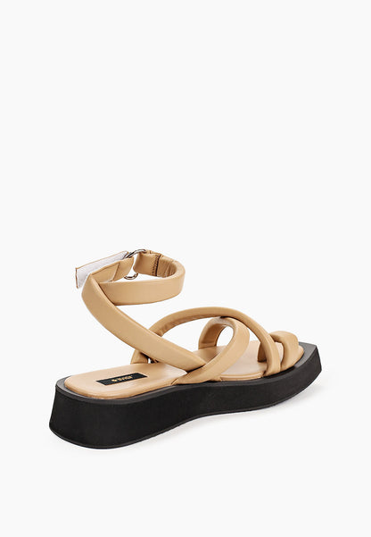 Rear view of beige crossover sandals showing ankle wrap and silver-tone D-ring
