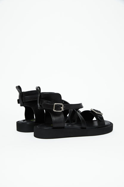Rear side view of black leather harness sandals with structured heel panels