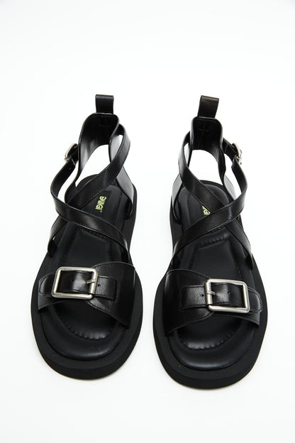 Top view of black genuine leather sandals with crossover straps and antique-silver buckles