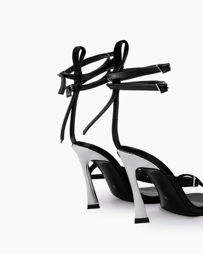 Rear view of black leather wrap heels showing sculptural flared heels and ankle straps