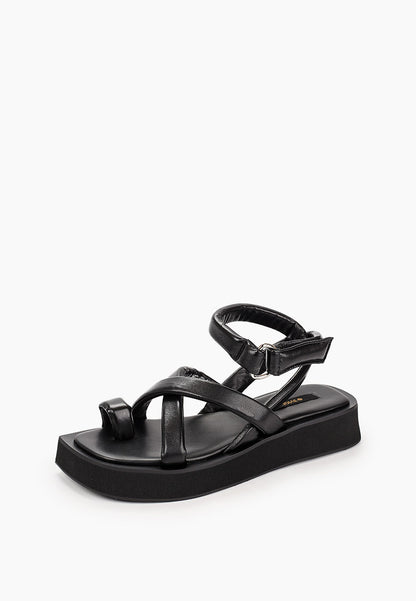 Three-quarter view of black leather platform sandals with crossover straps and toe loop