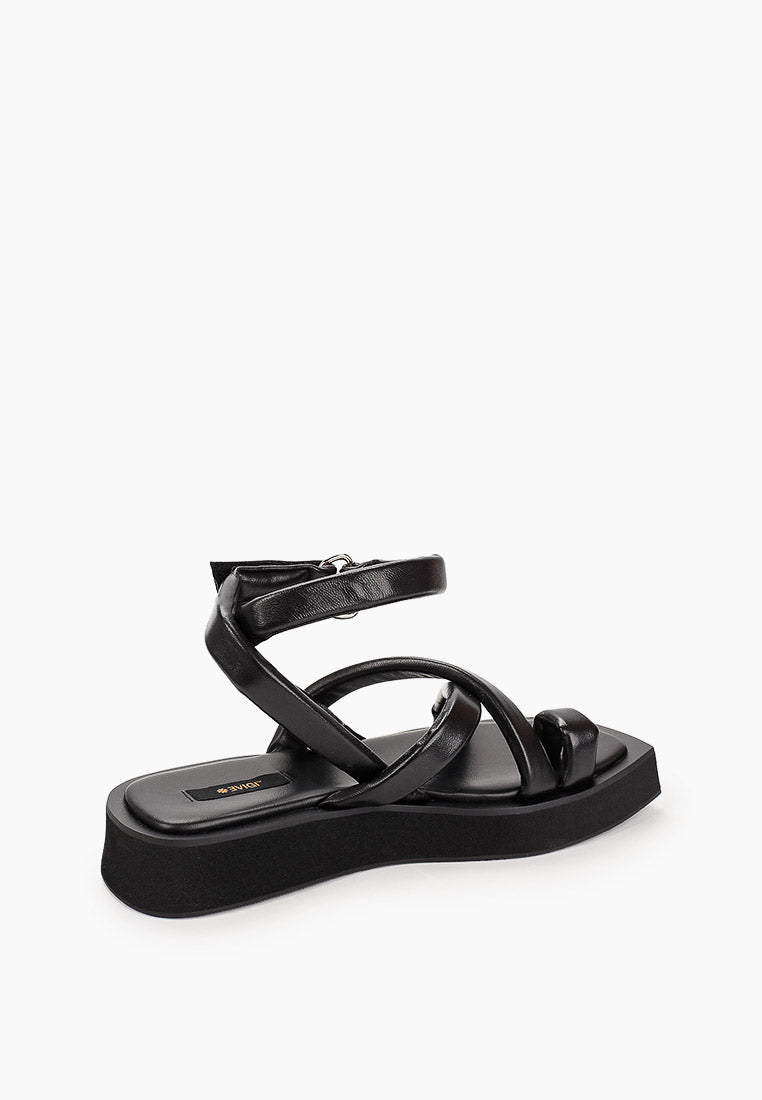 Rear side view of black leather sandals showing padded ankle strap and sculpted platform