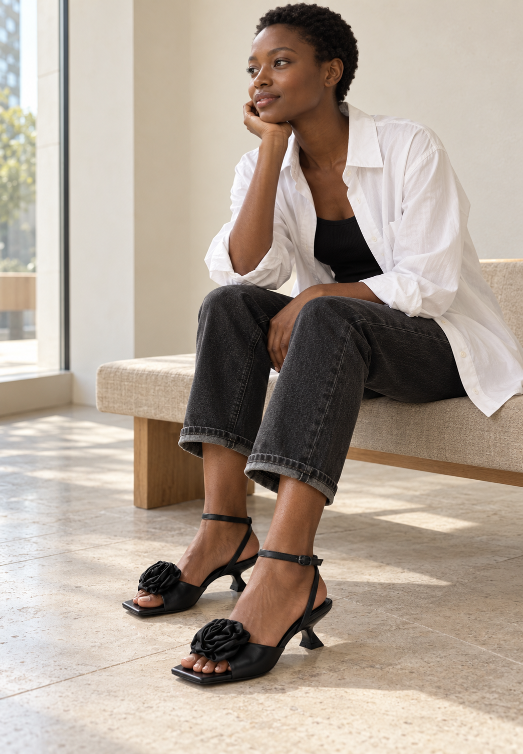 Black rosette sandals styled with charcoal denim in a modern interior