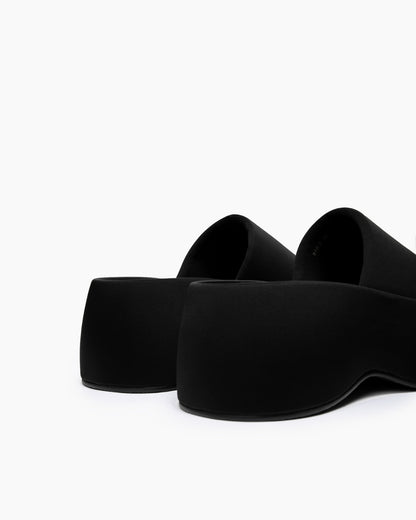 Rear view of black textile platform slides showing the sculpted sole profile