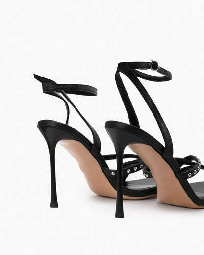 Rear view of black studded leather heels showing slim ankle straps and stiletto heels