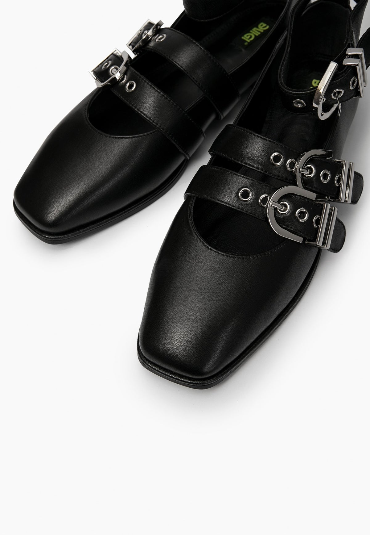 Close-up of black leather ballet flats showing square toes, eyelets and silver buckles