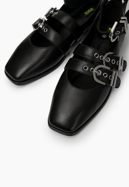 Close-up of black leather ballet flats showing square toes, eyelets and silver buckles