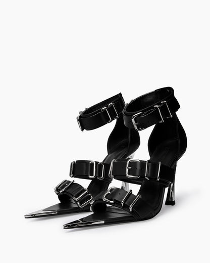 Pair of black leather heels with wide straps, oversized chrome buckles and pointed toe caps