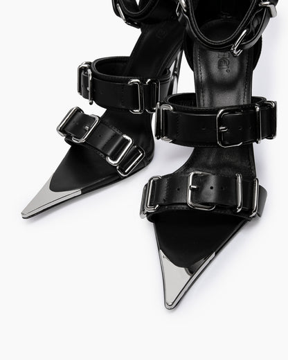 Close-up of wide black leather straps, oversized chrome buckles and pointed toe caps