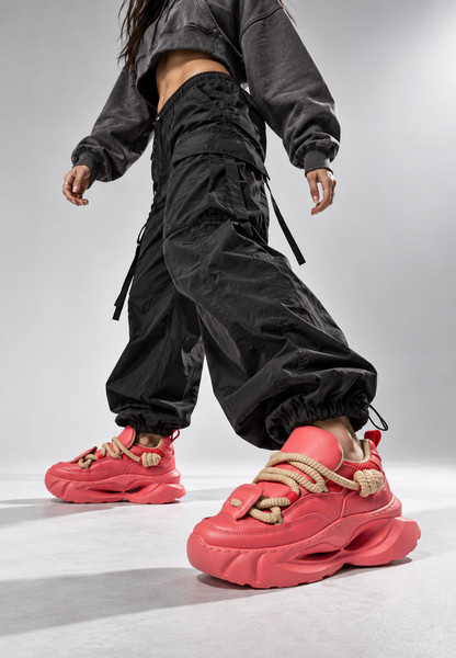 Low-angle streetwear styling of coral sculpted-sole sneakers in motion