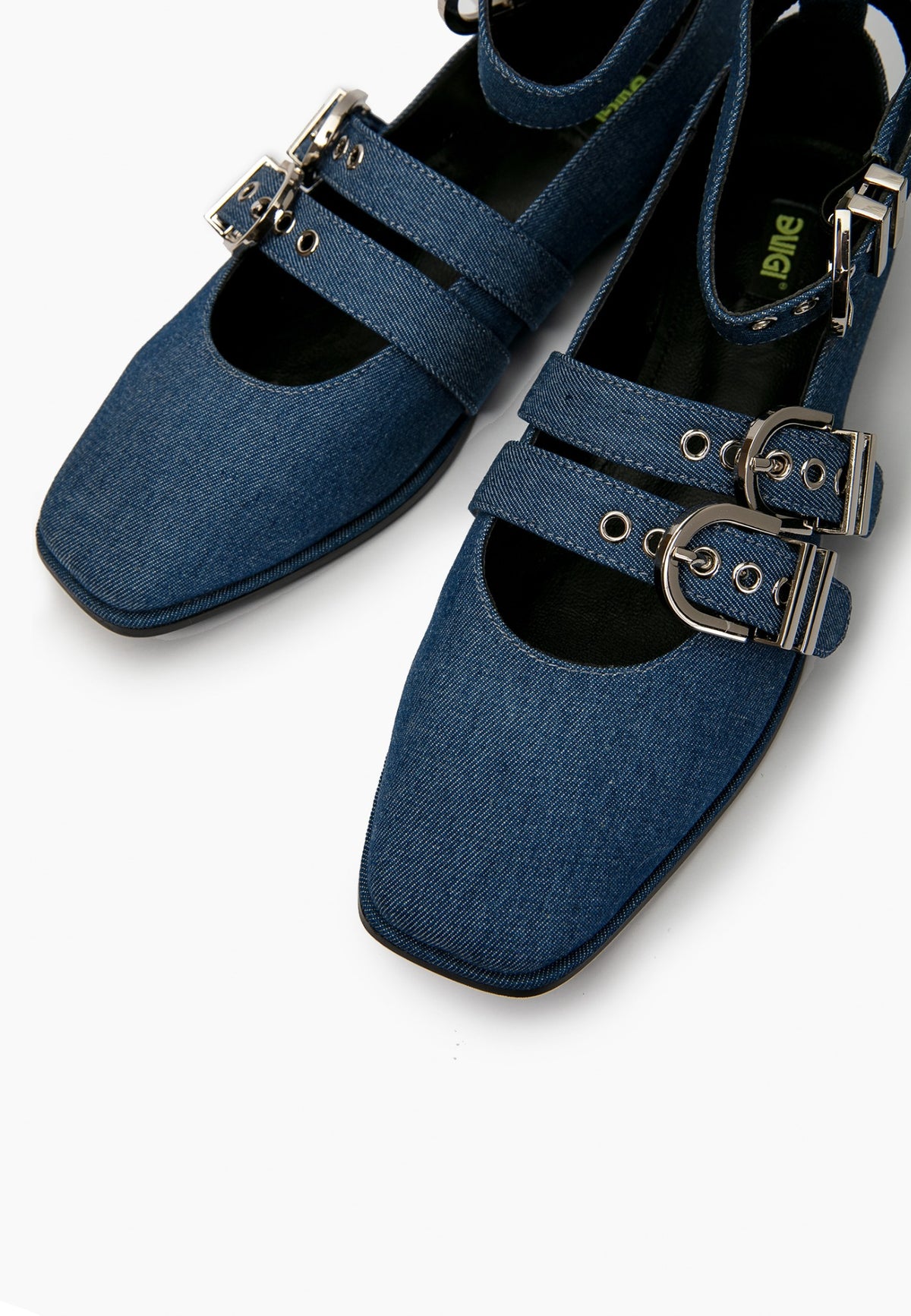 Close-up of blue denim ballet flats showing square toes, eyelets and silver buckles