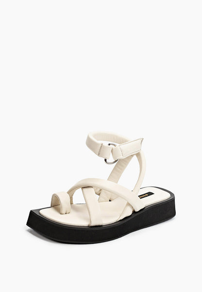 Front three-quarter view of ivory leather sandals with toe loop and sculpted black flatform