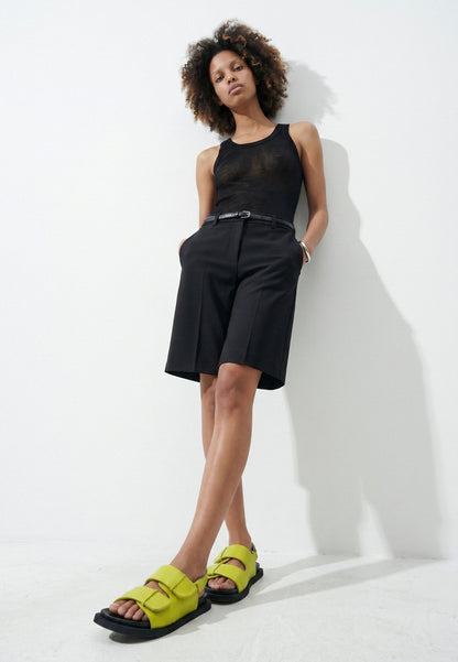 Woman styling lime green padded leather sandals with a black outfit