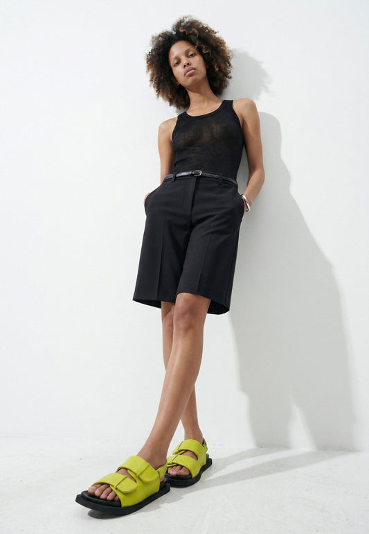 Woman styling lime green padded leather sandals with a black outfit
