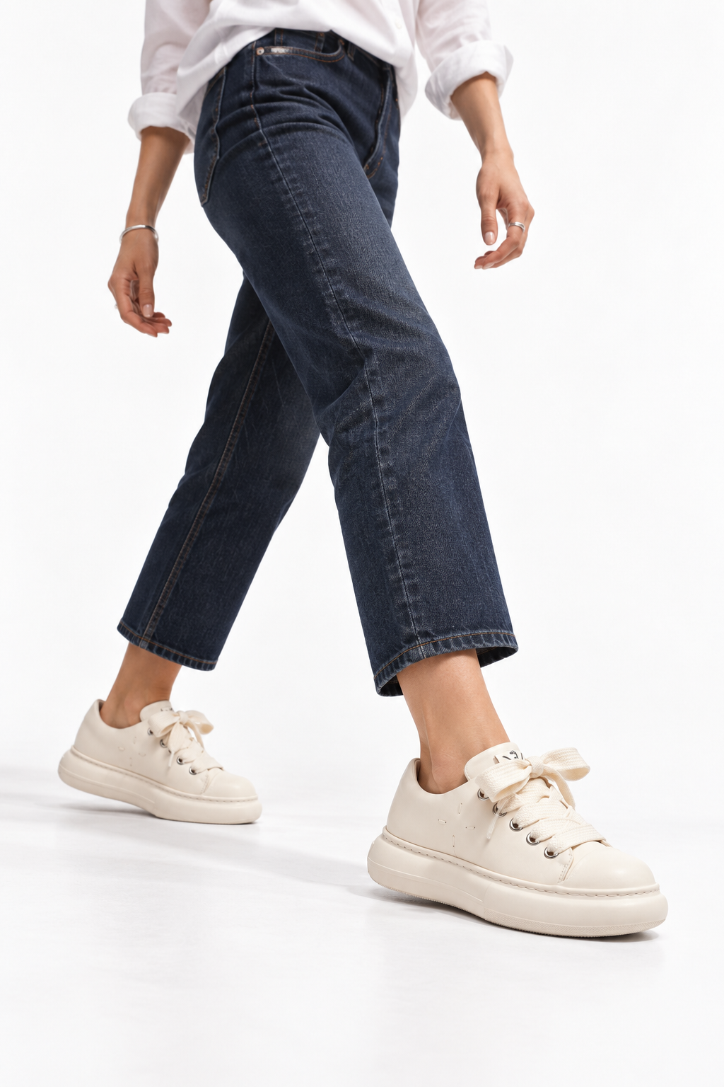 Close fashion view of milky leather platform sneakers worn with cropped denim