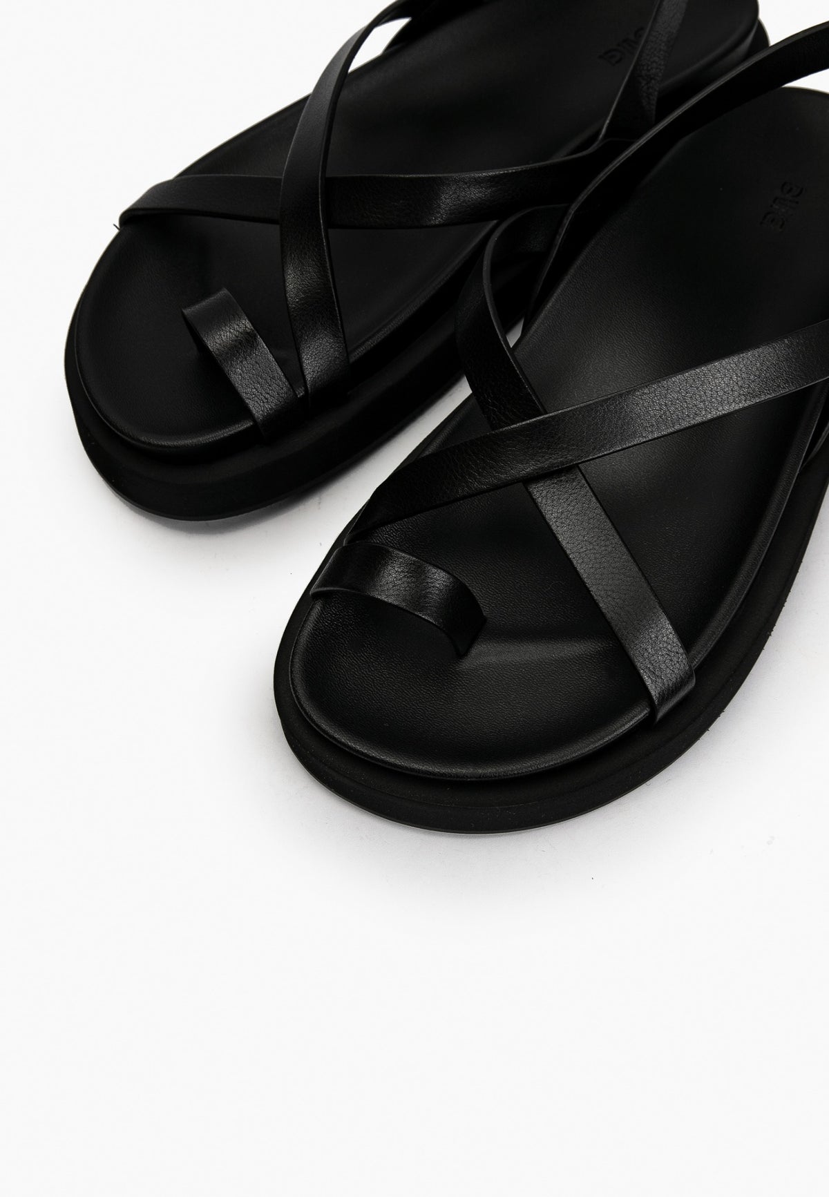 Close-up of smooth black leather straps and cushioned footbed