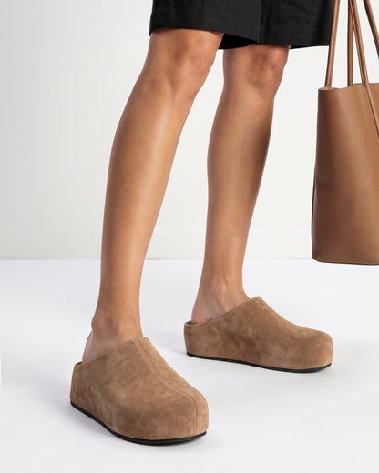 Taupe suede platform clogs worn with black shorts